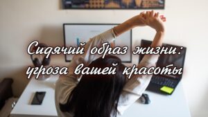 Изображение представляет собой откровенную фотографию, на которой изображена обстановка домашнего офиса. На макете представлен белый письменный стол с элегантным современным дизайном. На письменном столе находится частично открытый ноутбук с черным корпусом и прикрепленной к его поверхности запиской. Рядом с ноутбуком на подставке лежит смартфон в темном корпусе и пара черных наушников-вкладышей. На большом мониторе отображается график с синими и красными полосами, показывающий визуализацию данных. Над монитором на стене висит плакат с картой мира на темном фоне с золотыми вставками. На снимке изображен человек с черными волосами средней длины, если смотреть сзади, который вытягивает руки вверх. Человек одет в светлую рубашку с длинными рукавами. Общая атмосфера минималистична и организованна, что позволяет создать продуктивное рабочее пространство.