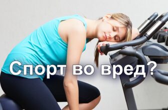 Изображение представляет собой цветную фотографию, изображающую обстановку спортзала, на которой изображена молодая женщина, отдыхающая на велотренажере. Изображение горизонтальное, на переднем и заднем плане изображено несколько тренажеров. На женщине со светлой кожей и прямыми каштановыми волосами, зачесанными назад, бирюзовый топ без рукавов и черные леггинсы. Она сидит на велосипеде, наклонившись вперед, положив голову на руль, с закрытыми глазами, что говорит об усталости или отдыхе. Современные велотренажеры оснащены цифровыми дисплеями и черно-серыми компонентами. На заднем плане - простая белая стена, что усиливает внимание к предмету и оборудованию. Общая атмосфера создает ощущение усталости или расслабления в фитнес-среде.