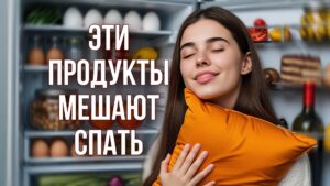 Изображение представляет собой цветную фотографию молодой женщины, стоящей перед открытым холодильником. У нее длинные каштановые волосы и светлая кожа, она зевает, держа в руках оранжевую подушку. Холодильник забит различными продуктами, включая яйца, фрукты, овощи и бутылку вина. На дверных полках расположены банки с цитрусовыми, а в главном отделении - помидоры, грибы и торт. На заднем плане - простая серая стена, а общая обстановка создает впечатление непринужденной домашней обстановки.