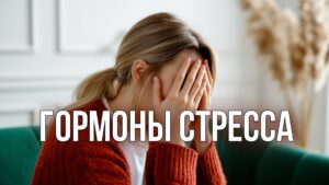 Изображение представляет собой откровенную фотографию в помещении, на которой изображена женщина, сидящая на зеленом диване. У нее светлая кожа и длинные светло-каштановые волосы, собранные сзади в свободный хвост, гормоны стресса. Ее лицо закрыто руками, которыми она прикрывает глаза, что наводит на мысль о том, что в этот момент она переживает горе или размышляет. На ней свитер кремовой вязки поверх белой рубашки. На заднем плане, мягко сфокусированном, видны белые стены с декоративной лепниной и высокая сухая пампасная трава в вазе, что придает комнате естественный вид. Общая атмосфера спокойная, но в то же время погруженная в себя, с преобладанием нейтральных тонов.